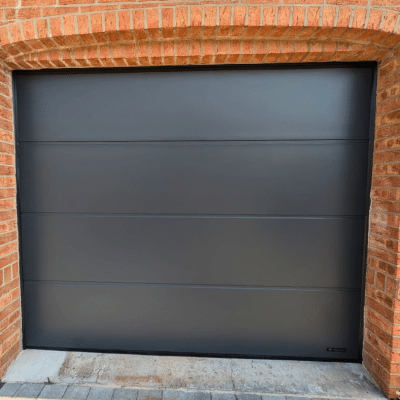 porte de garage sectionnelle UniPro WIŚNIOWSKI gris anthracite installée sur une façade en briques à Landas