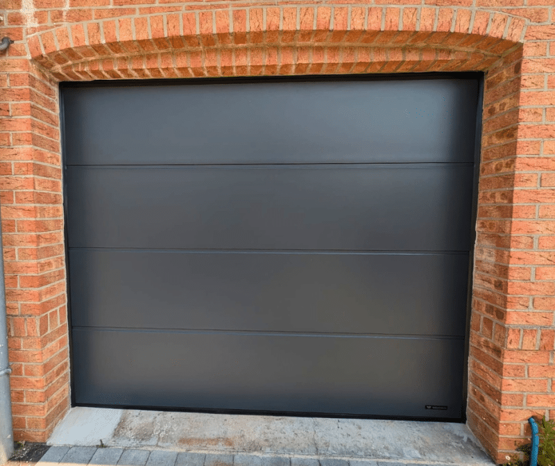 porte de garage sectionnelle UniPro WIŚNIOWSKI gris anthracite installée sur une façade en briques à Landas